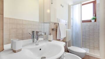 A modern bathroom with a large sink, toilet, and shower area.