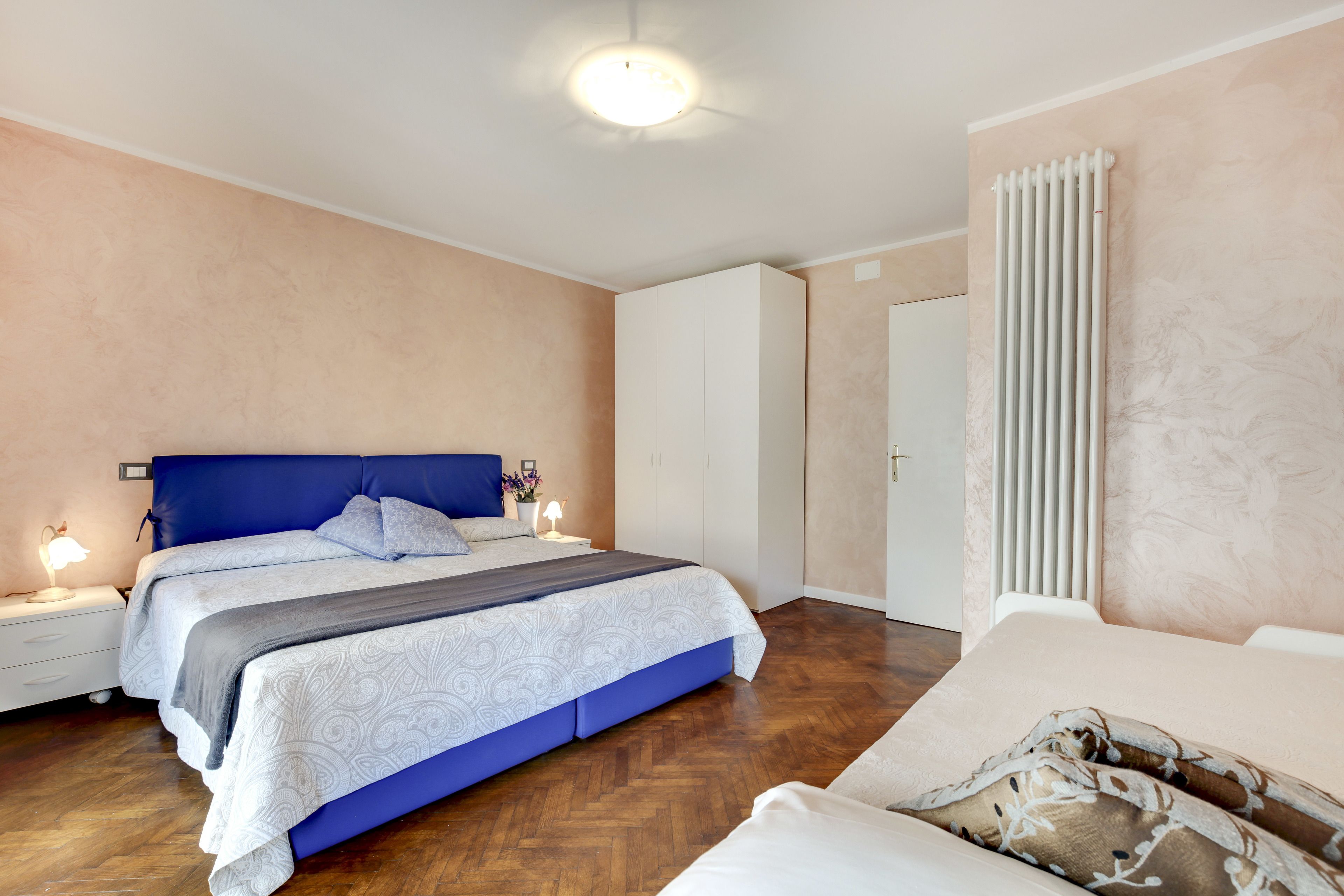 Una camera da letto con un letto grande, comodini, un termosifone e un armadio.