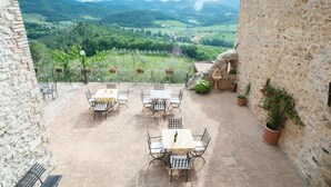 A patio with tables and chairs, overlooking a scenic valley. - Il Castello di Perchia (Spoleto)