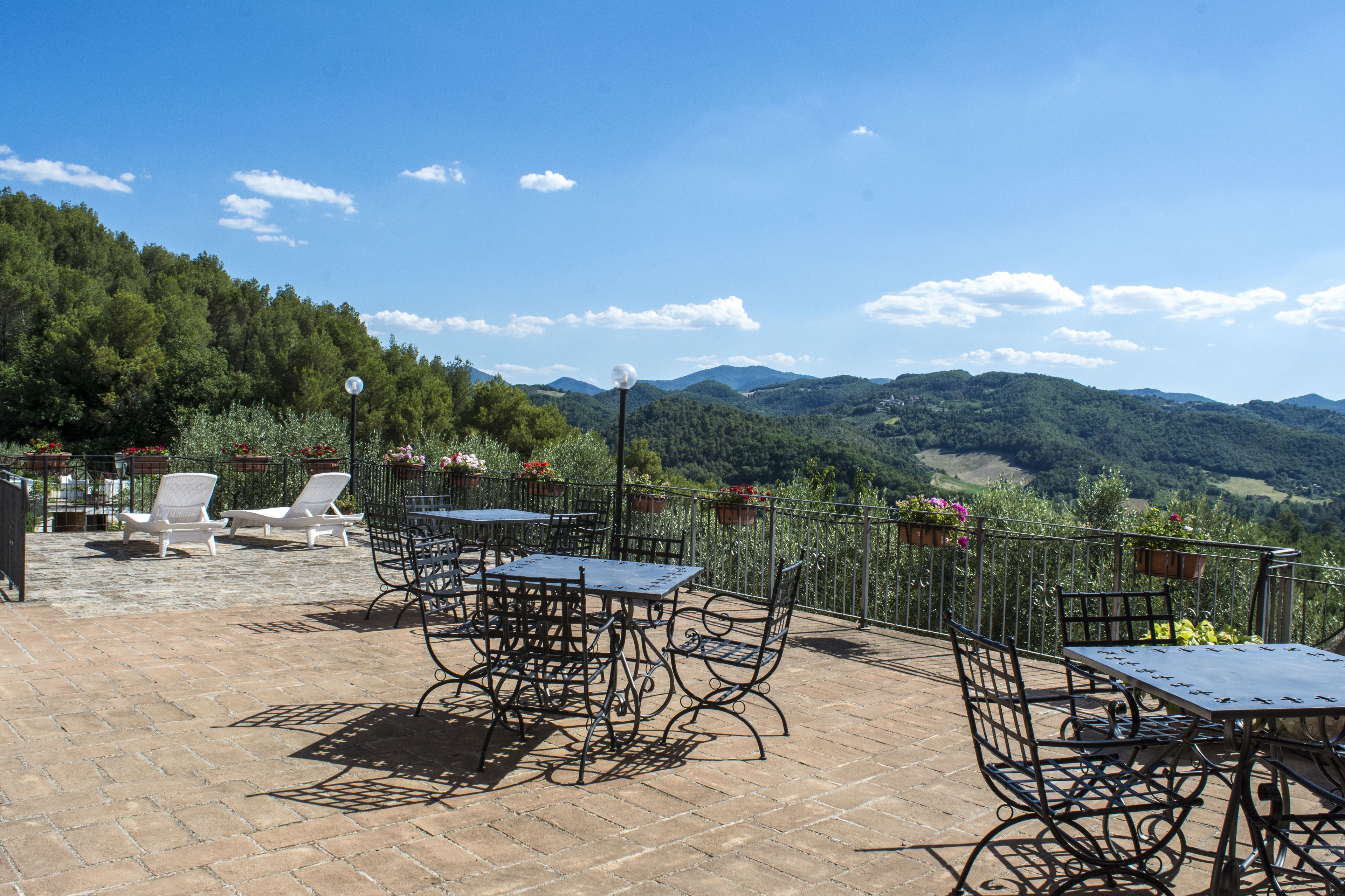 Un patio al aire libre con mesas y sillas, con vistas a un paisaje montañoso.