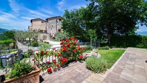 A stone building with a balcony, surrounded by greenery and a clear sky. - Il Castello di Perchia (Spoleto)