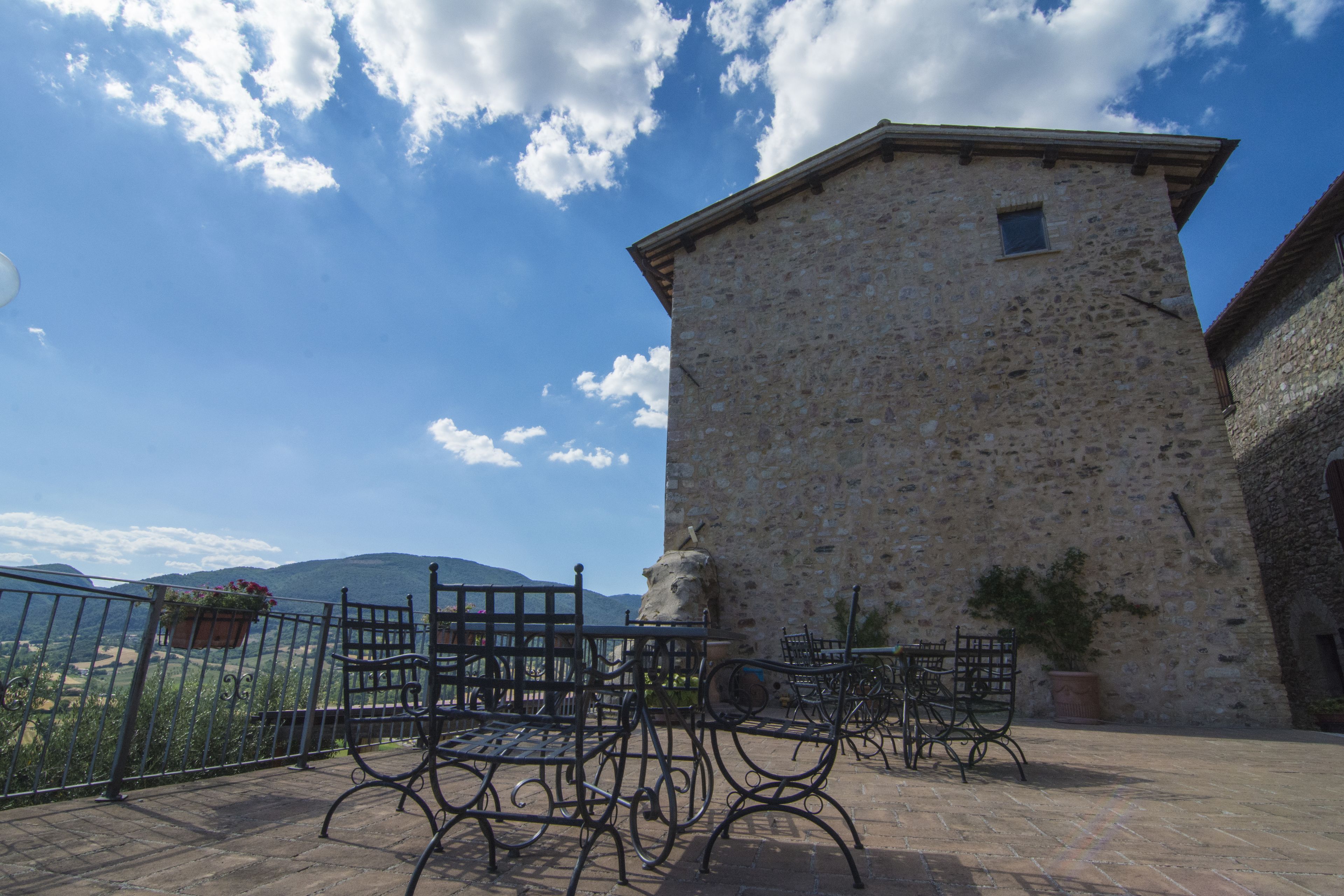 A stone building with a balcony and outdoor seating.