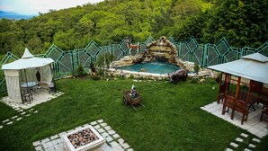 Un jardín trasero con un estanque, un pabellón y una casita de juegos de madera.