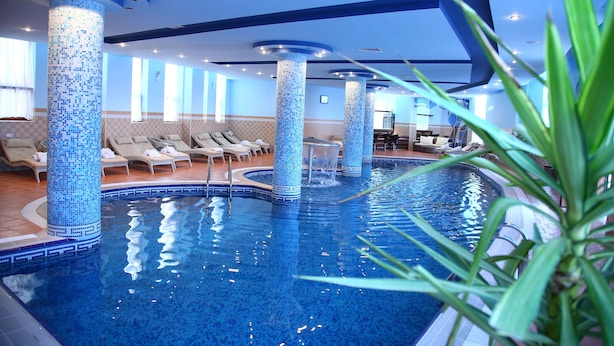 Una piscina interior con columnas de azulejos, sillas de descanso y una vista despejada del área de la piscina.