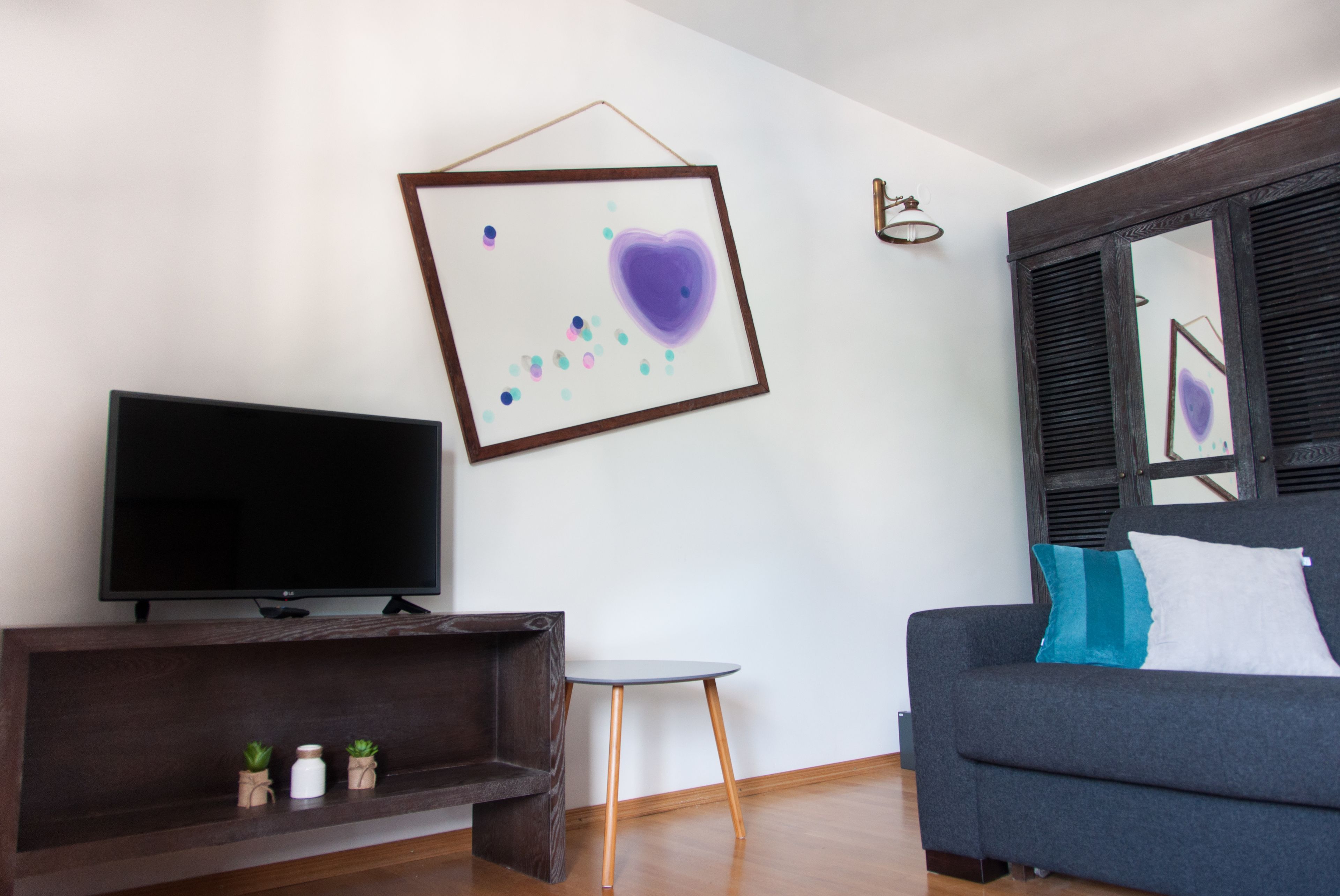 Un salon moderne doté d’un téléviseur à écran plat, d’une table basse, d’un canapé avec des coussins et d’une œuvre d’art abstraite encadrée accrochée au mur.