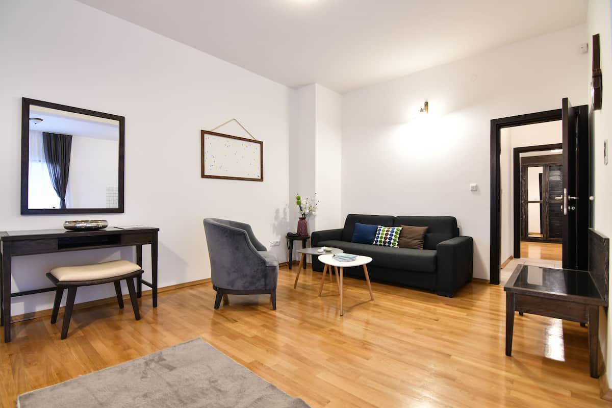 Ein modernes Wohnzimmer mit Sofa, Sessel, Couchtisch und Schreibtisch mit Stuhl.
