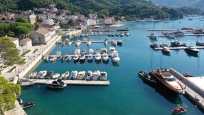 A marina with numerous boats docked, surrounded by residential buildings and mountains in the background.