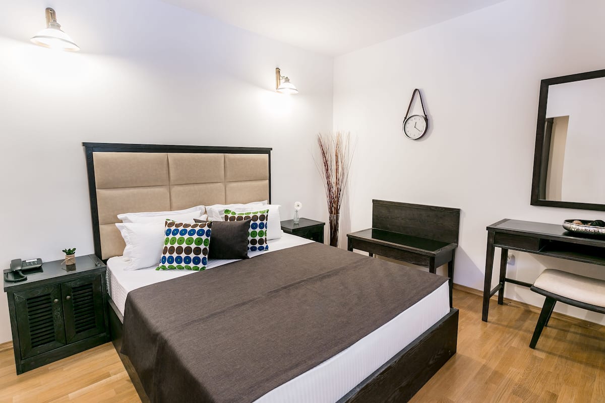 Ein modernes Hotelzimmer mit einem großen Bett, Nachttischen, einem Schreibtisch und einem Spiegel.
