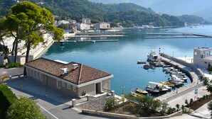 Uma cidade costeira com um porto, edifícios e montanhas ao fundo.