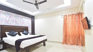 A modern bedroom with a large bed, a ceiling fan, and a patterned curtain. - JK Residency (Tiruchirappalli)