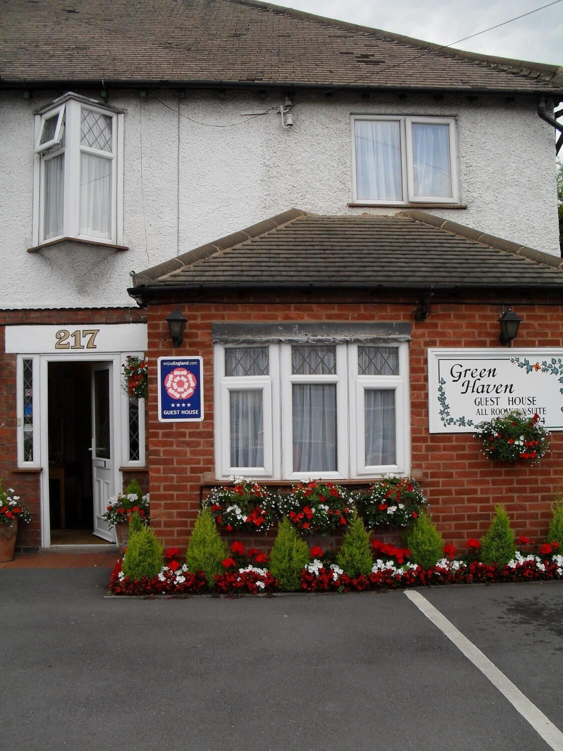 A two-story building with a sign for 'Green Haven Guest House' and a '217' address number.