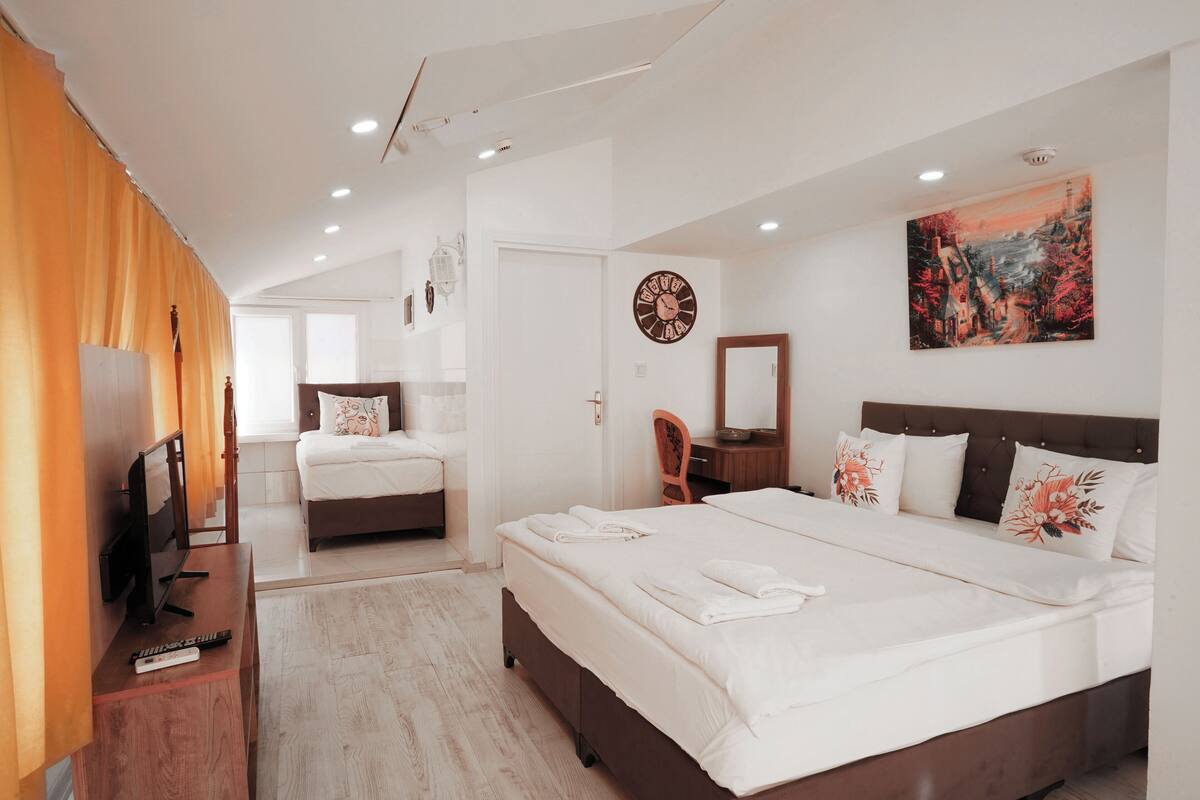 A modern hotel room with a large bed, a desk with a computer, and a television.