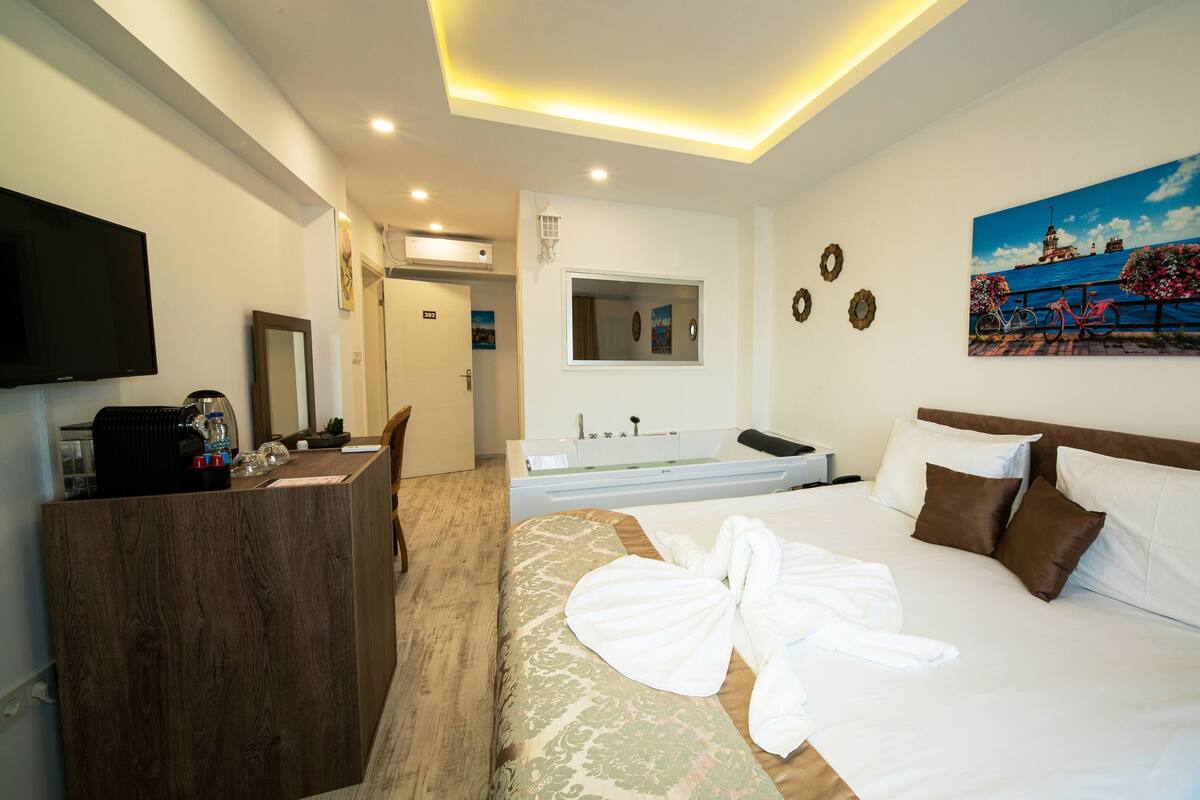 A hotel room with a bed, a desk, a TV, and a bathroom.