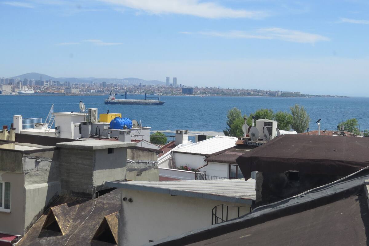 A rooftop with satellite dishes, a large water body, and distant cityscape.