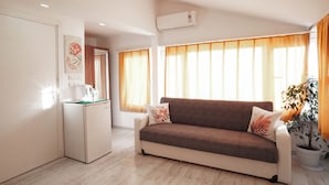 Una sala moderna con un sofá, una pequeña kitchenette y una planta en maceta.