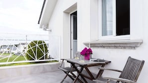 Un balcon avec une table et des chaises, un pot de fleurs et une vue sur les environs.