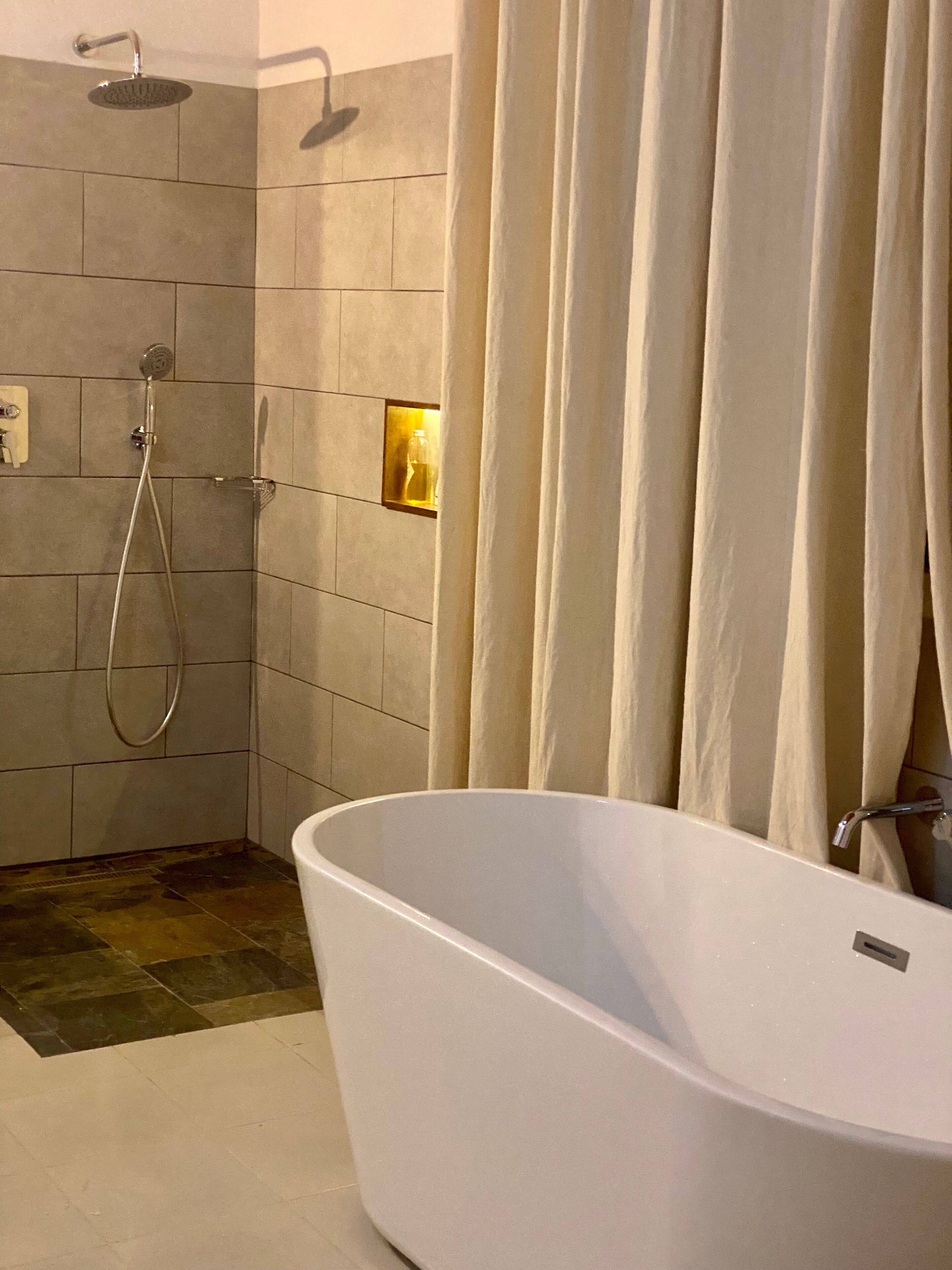 Une salle de bain moderne avec une baignoire sur pieds, un espace douche et un porte-serviettes.