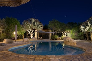 Alberca al aire libre, sombrillas en la alberca y camastros