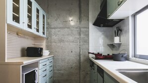 Una cocina pequeña con armarios blancos, un microondas y un lavabo.