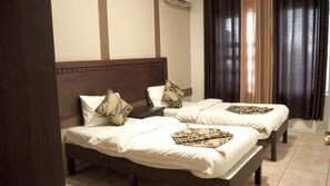 A hotel room with two single beds, each with a patterned bedspread and matching pillows.
