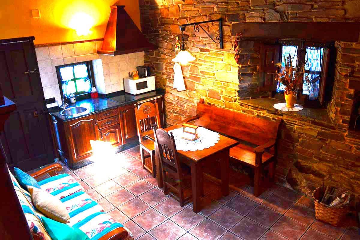 A cozy kitchen with a stone wall, a wooden table, and a bench.
