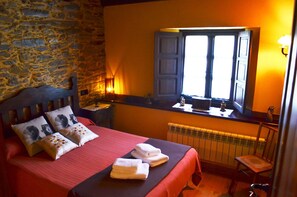 Cozy retreat with a rustic stone wall, plush bed, and charming window seat.