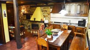Une cuisine rustique avec un mur en pierre, des armoires en bois, une table à manger avec des chaises et une cheminée.