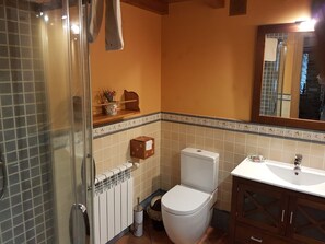 Features a glass shower enclosure, white toilet, and sink with a wooden cabinet, set against decorative tile walls and a mirror above.