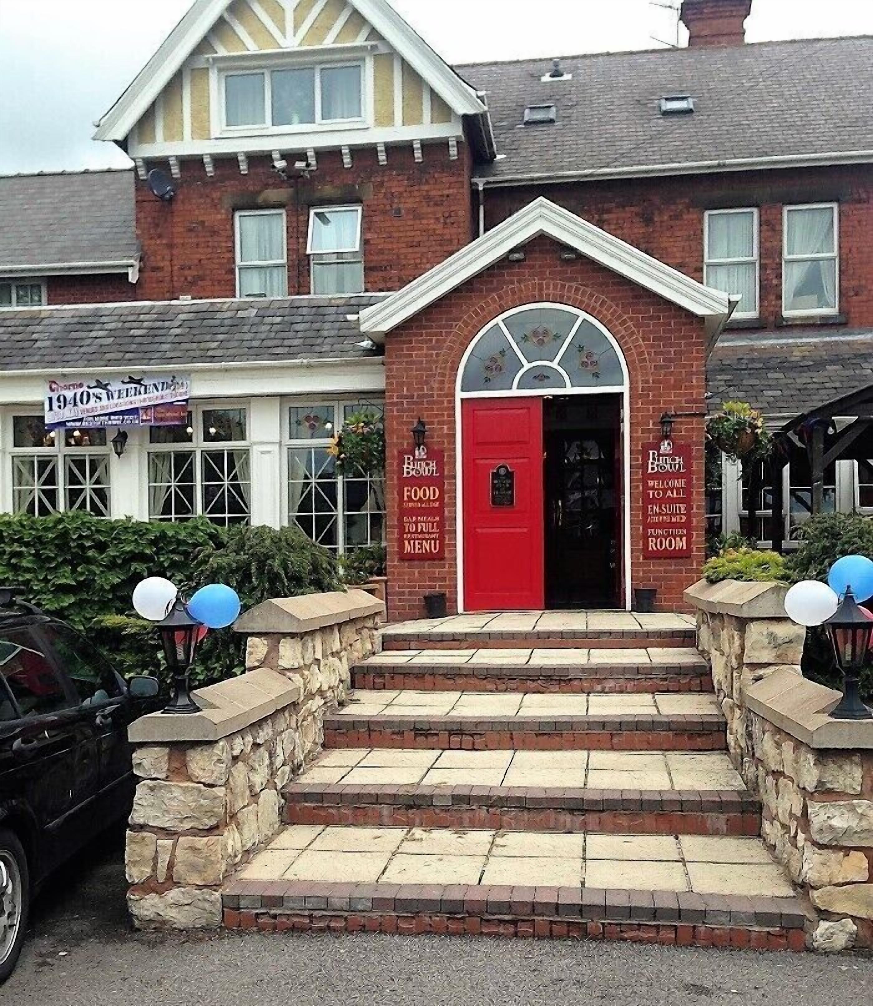 A building with a red entrance door, steps leading up to it, and a sign that reads "1940's Weekend Club."