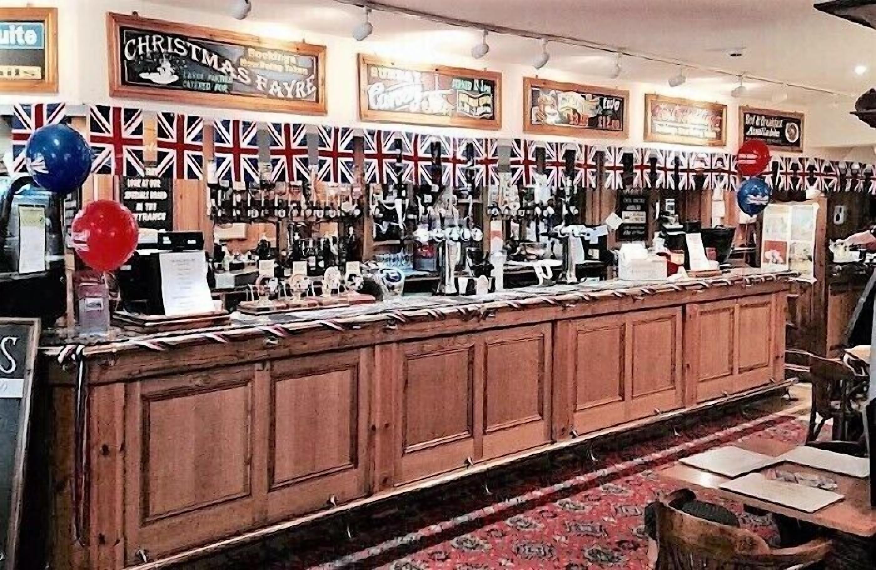 A bar area with wooden cabinets, a red carpet, and various decorations including balloons and flags.
