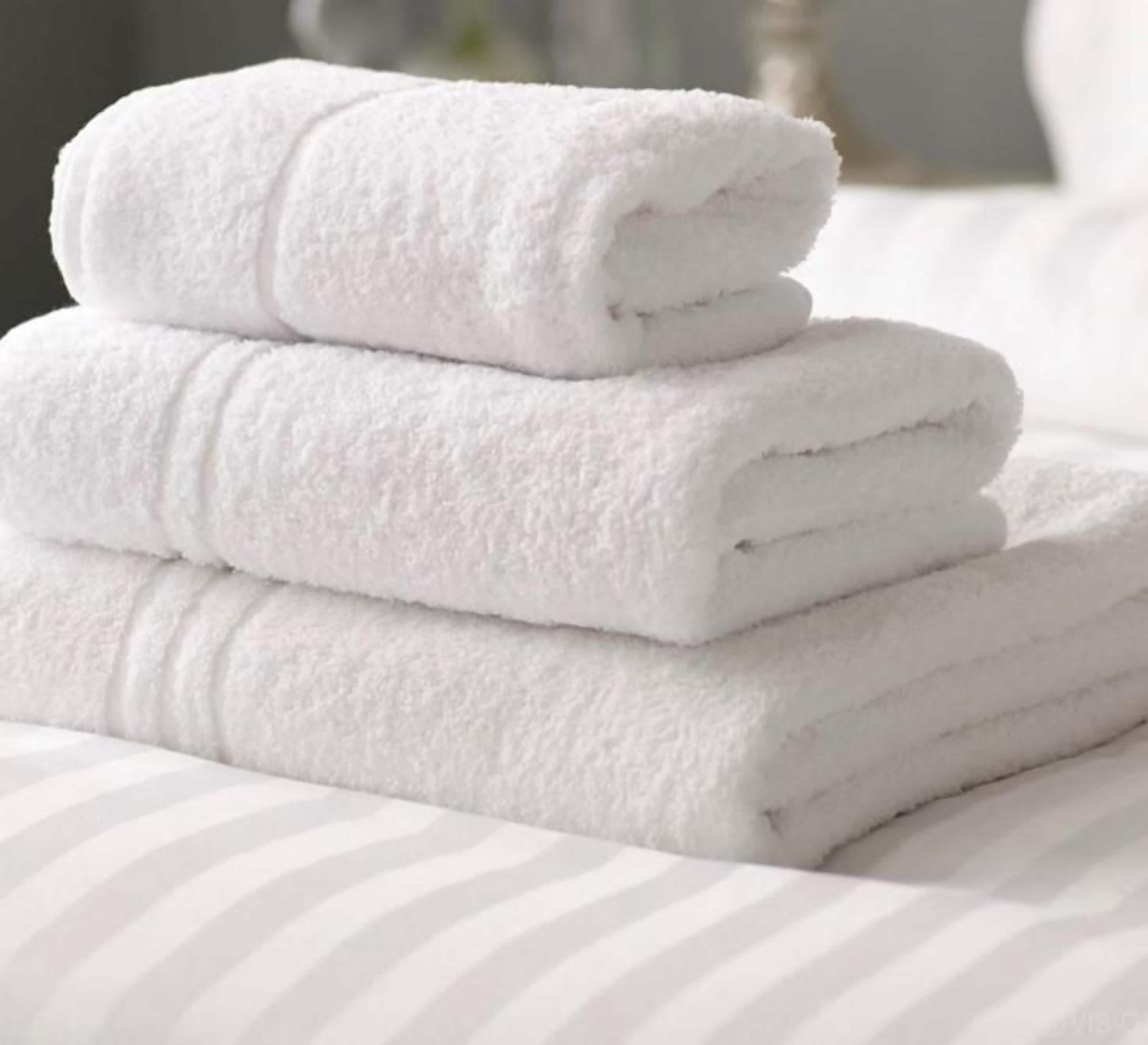 Un montón de toallas blancas sobre una cama con ropa de cama a rayas.