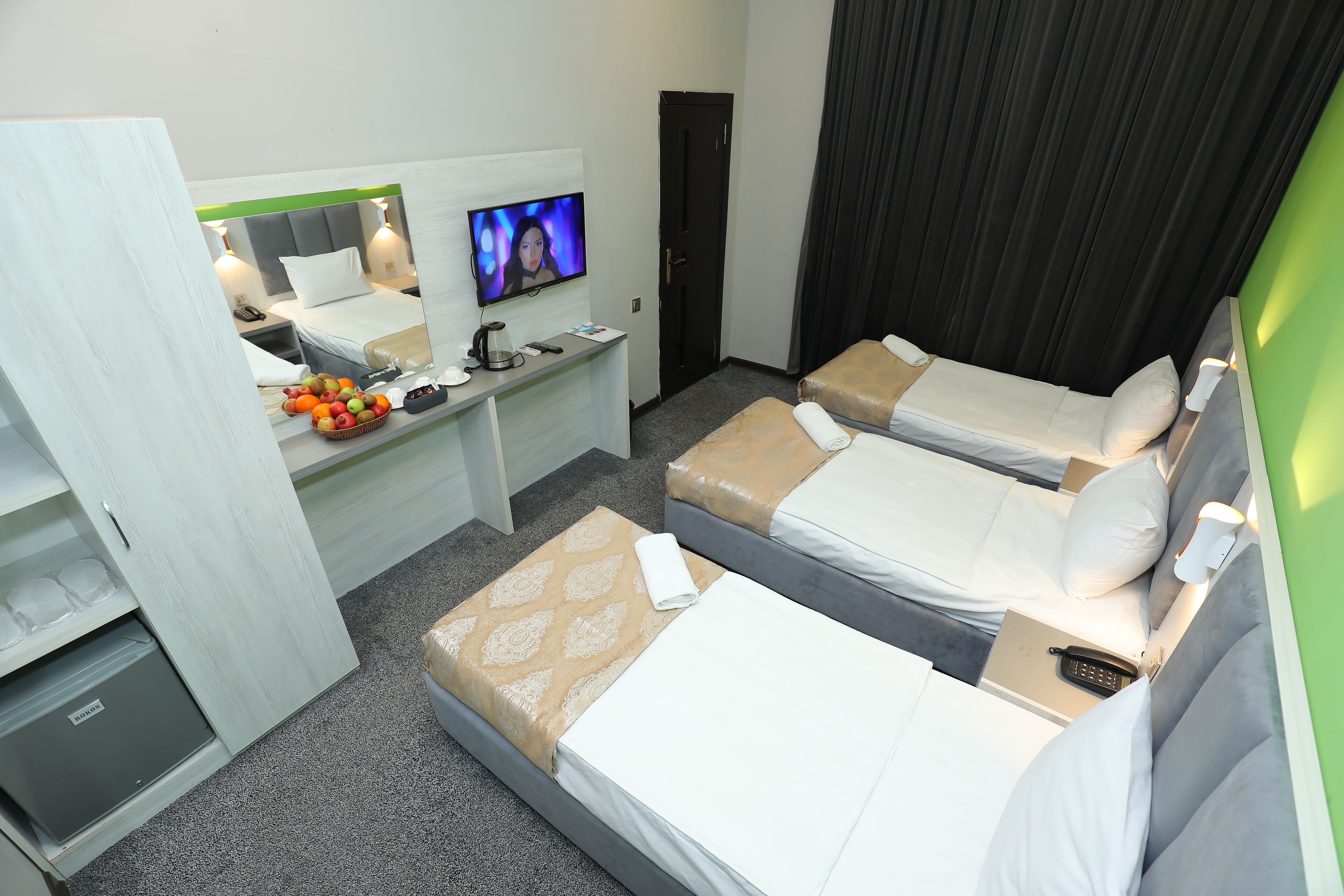 Ett hotellrum med två sängar, ett skrivbord med en dator, en tv och en minibar.
