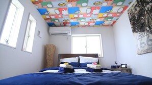 A hotel room with a bed, a window, an air conditioner, and a ceiling with a comic book pattern. - Guest House Rion (Yomitan)