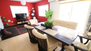 A dining area with a table, chairs, a television, and a plant. - Guest House Rion (Yomitan)