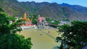 A riverside town with a prominent temple and a bridge. - Kunwar Residency (Narendranagar)