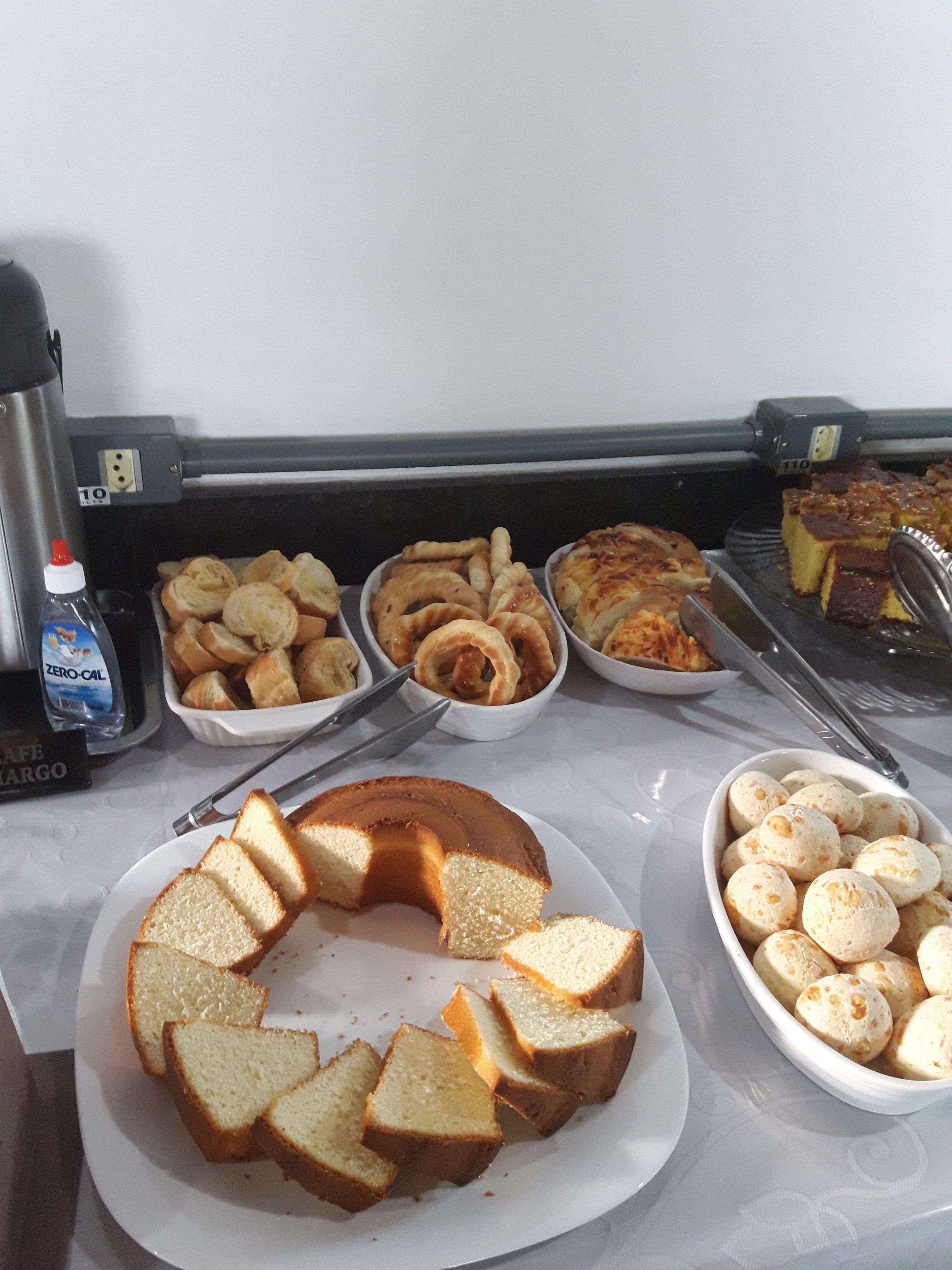 A buffet table with various baked goods including bread, pastries, and cakes.