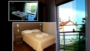Une chambre d’hôtel avec un lit, une table de chevet et une fenêtre donnant sur un immeuble et de la verdure.
