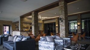 Eine moderne Lobby mit Sofas, einer Bar und einer Sitzecke mit einem Tisch, auf dem eine Nachricht steht.
