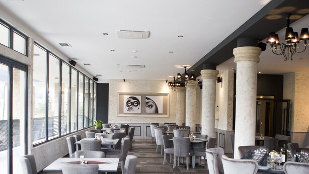 Ein geräumiges Restaurant mit hohen Decken, großen Fenstern und einem modernen Ambiente.