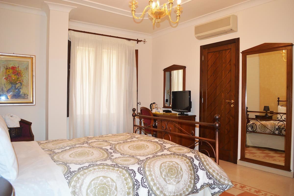 Een slaapkamer met een bed, een televisie, een kledingkast en een spiegel.