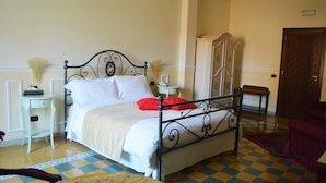 A neatly arranged bedroom with a bed, bedside tables, a wardrobe, and a checkered floor. - Hotel Palazzo Krataiis (Scilla)