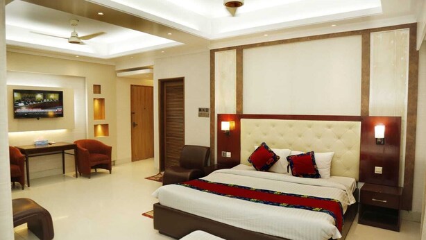 A hotel room with a large bed, a desk with a chair, a television, and a ceiling fan. - Sea Shell Residence (Dhaka)
