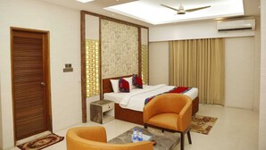 A hotel room with a bed, two chairs, a small table, a ceiling fan, and an air conditioning unit. - Sea Shell Residence (Dhaka)