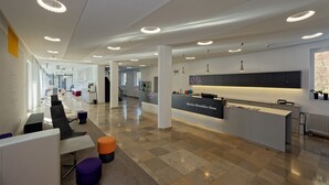Um espaço de escritório moderno com cubículos, uma mesa de recepção e uma copa.