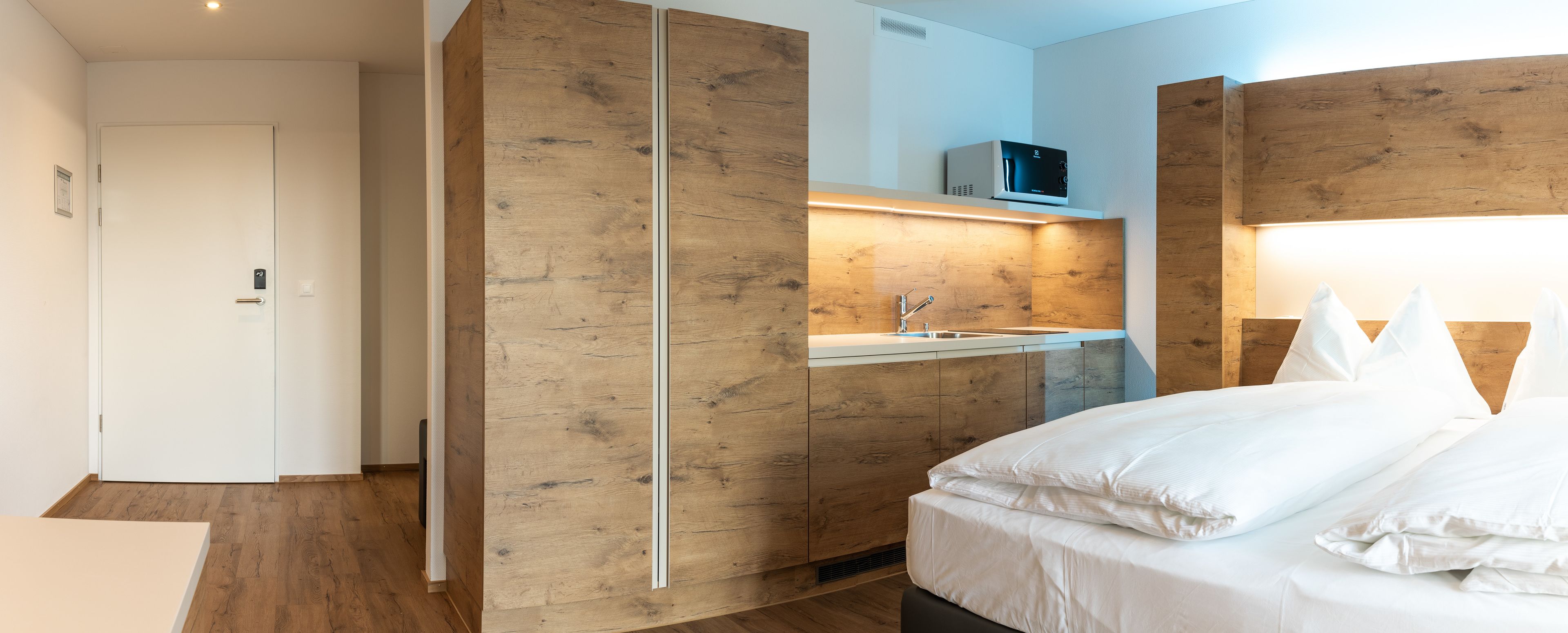 Un dormitorio moderno con una pared de acento de madera, un televisor integrado y una mesita de noche.