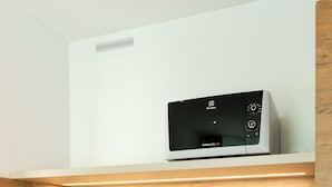 A kitchen with a built-in microwave, a sink, and wooden cabinetry. - Trip Inn Jet Hotel Zürich Airport (Ruemlang)