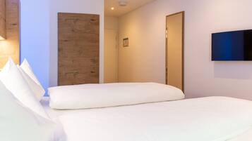 Une chambre d’hôtel avec un lit, un mur décoratif en bois, une porte et un téléviseur à écran plat fixé au mur.