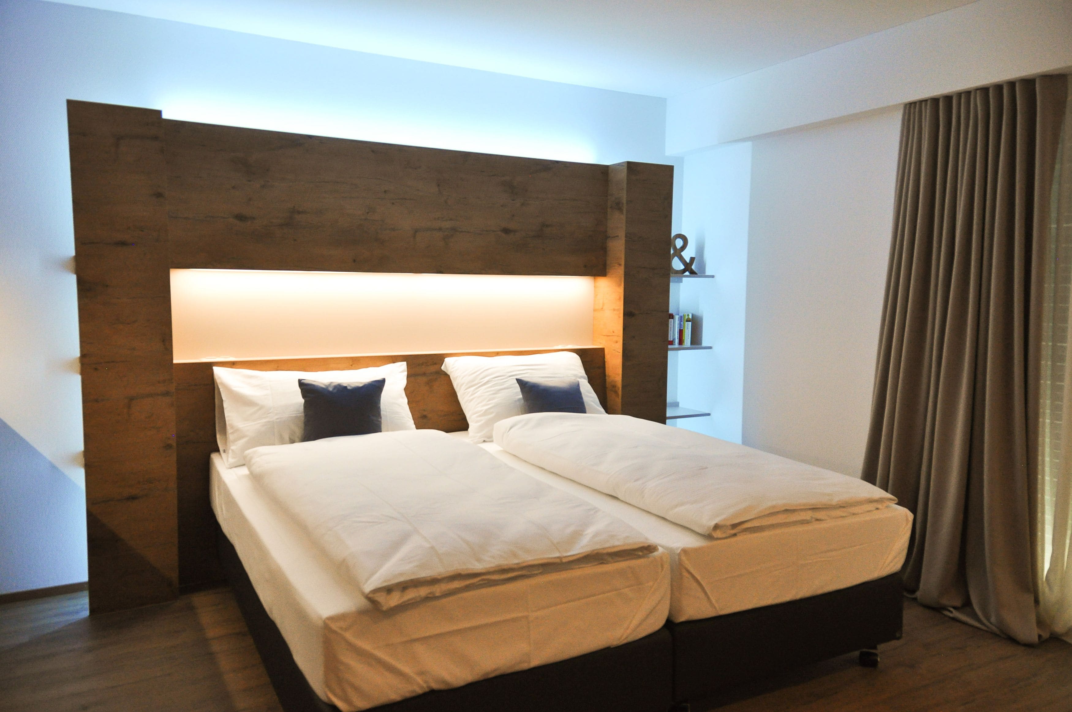 Una cama doble con cabecera de madera, ropa de cama blanca y una mesita de noche con lámpara.