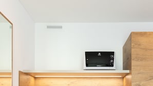 A modern kitchen with wooden cabinetry, a built-in microwave, and a stainless steel sink. - Trip Inn Jet Hotel Zürich Airport (Ruemlang)