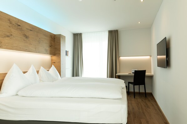 A modern hotel room with a large bed, a desk, a chair, and a TV mounted on the wall. - Trip Inn Jet Hotel Zürich Airport (Ruemlang)